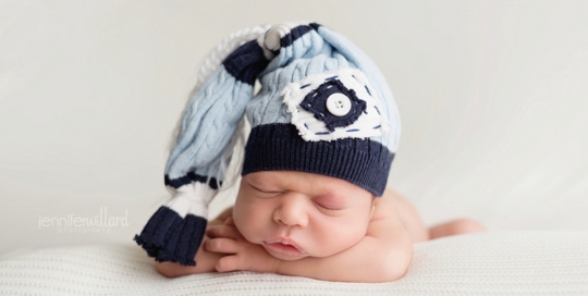 newborn photography on white blanket in studio with hat