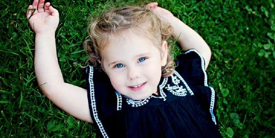 little girl laying on ground in black dress in park by kingston ontario children photographer