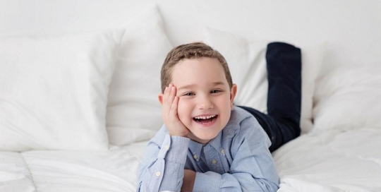 little boy lying on white bed at kingston children photography studio