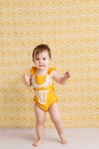 yellow-romper-yellow-backdrop-wood-white-floor-baby-girl-milestone-portrait-kingston-ontario-photography-studio