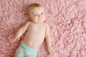 baby-girl-pink-rug-lying-down-mint-pants-flower-headband-kingston-photographer