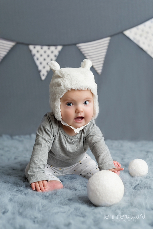 baby-girl-grey-white-banner-grey-backdrop-grey-flokati-snowballs-bear-hat-studio-photography