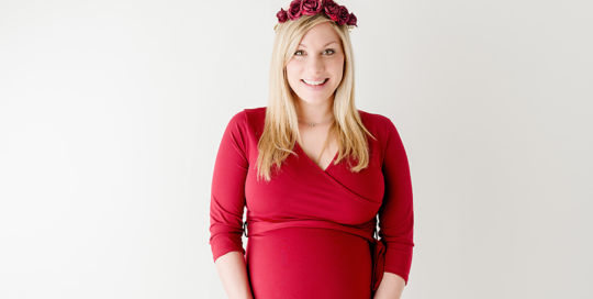 Maternity Picture of woman in red dress with red flower crown in white studio Kingston Ontario