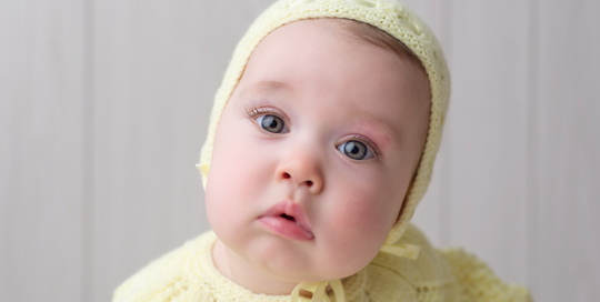 baby boy 6 month picture on white wood backdrop with vintage yellow hat and sweater