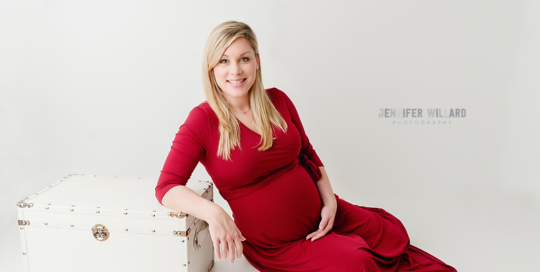 maternity picture of woman in red dress against white leather crate in kingston portrait studio