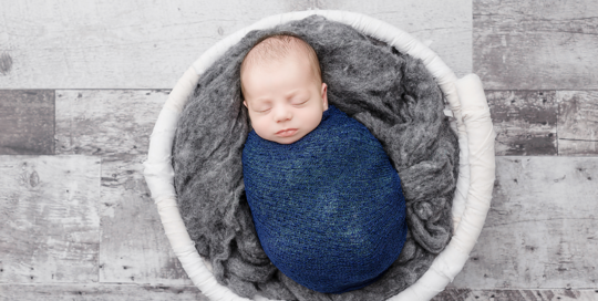 baby boy in blue wrap in white bucket on grey wood floor in kingston photography studio