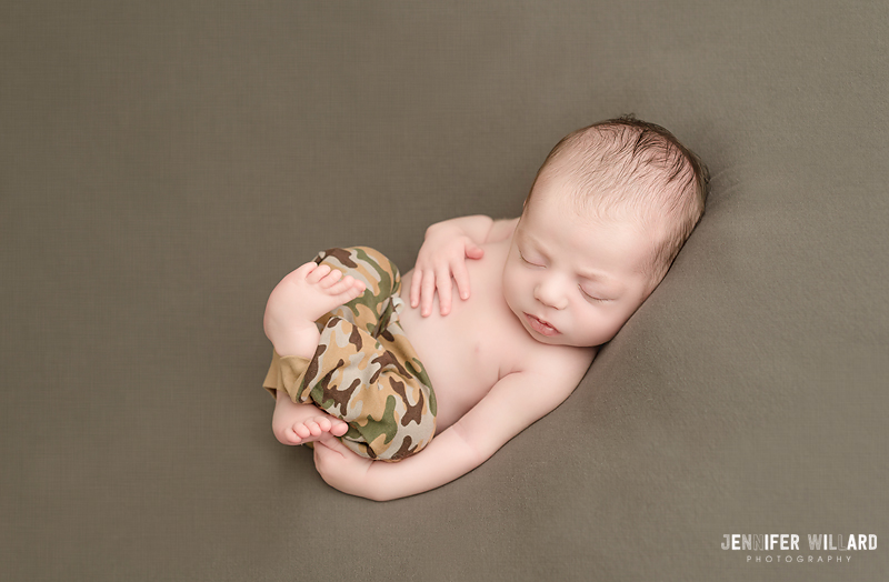 baby boy on back with camo pants in kingston portrait studio