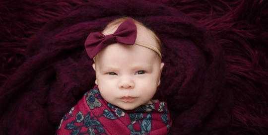 baby girl on purple fur in purple flower wrap with headband taken in kingston ontario baby studio