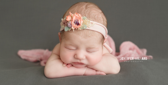 baby girl with pretty pink flower headband with pink wrap on grey blanket in kingston ontario baby photography studio