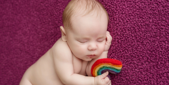 baby girl with rainbow felted prop on purple blanket in kingston ontario portrait studio