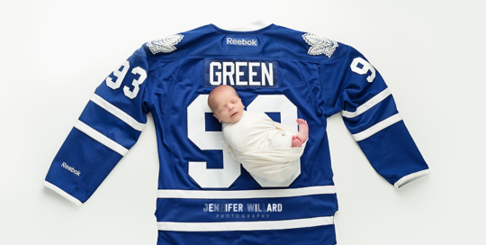 baby in white wrap on Toronto Maple Leaf jersey at kingston ontario baby photography studio