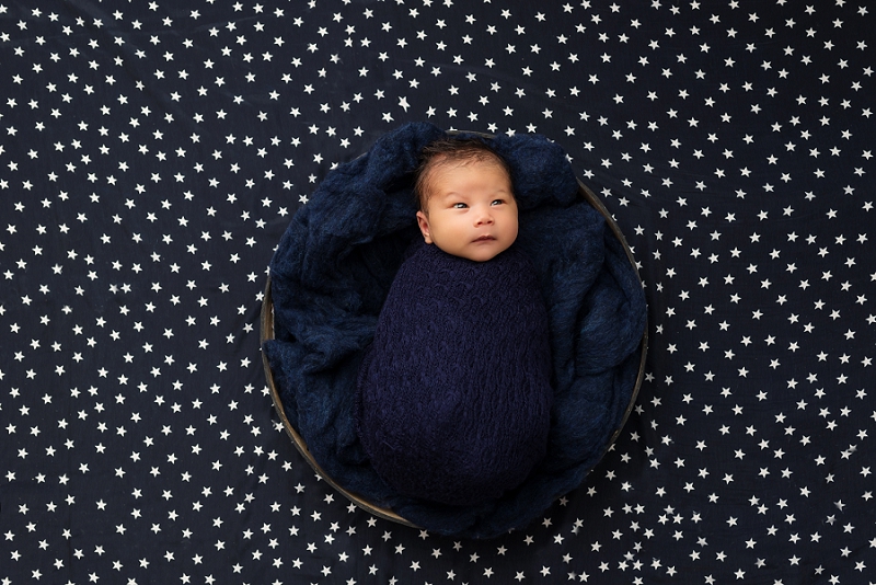 baby boy in navy blue wrap in black bowl on star backdrop by Belleville Newborn Photographer_0033