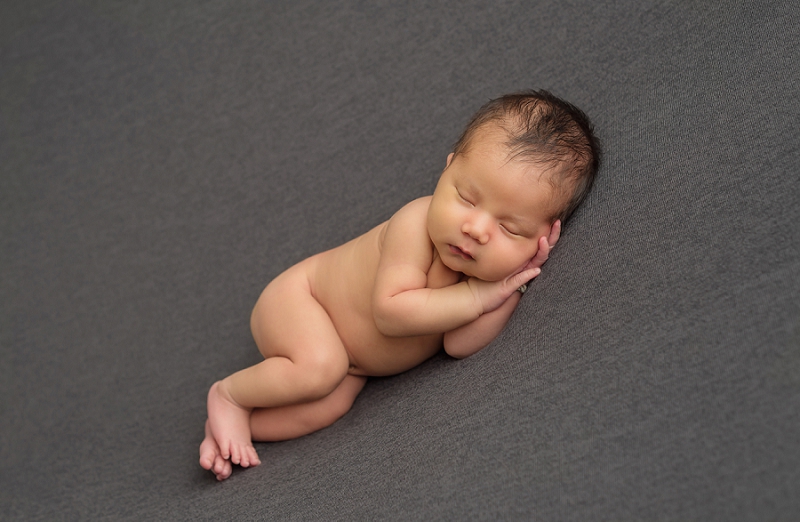 First Nations newborn baby boy laying on side on grey blanket by Belleville Newborn Photographer