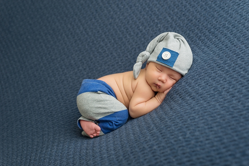 First Nations newborn boy in blue and grey striped pants and hat with white button on blue blanket by Belleville Newborn Photographer