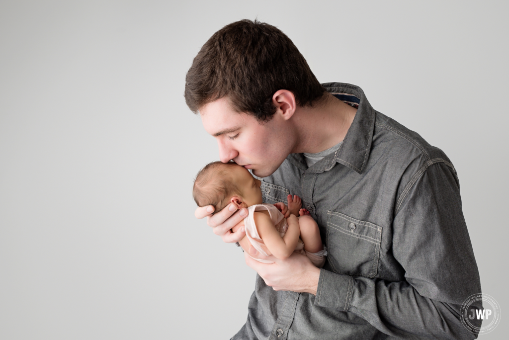 newborn baby girl with father kissing forehead Kingston Ontario Baby Photographer