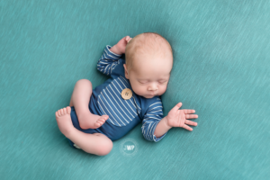 newborn-baby-on-back-blue-romper-blue-blanket-Kingston-Photographer