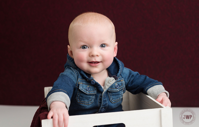 posed baby portrait 6 months old boy jean jacket burgundy backdrop Kingston Children Photographer