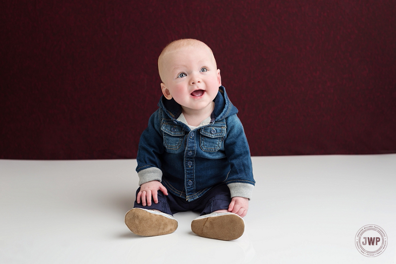 posed baby portrait 6 months old boy jean jacket burgundy backdrop Kingston Children Photographer