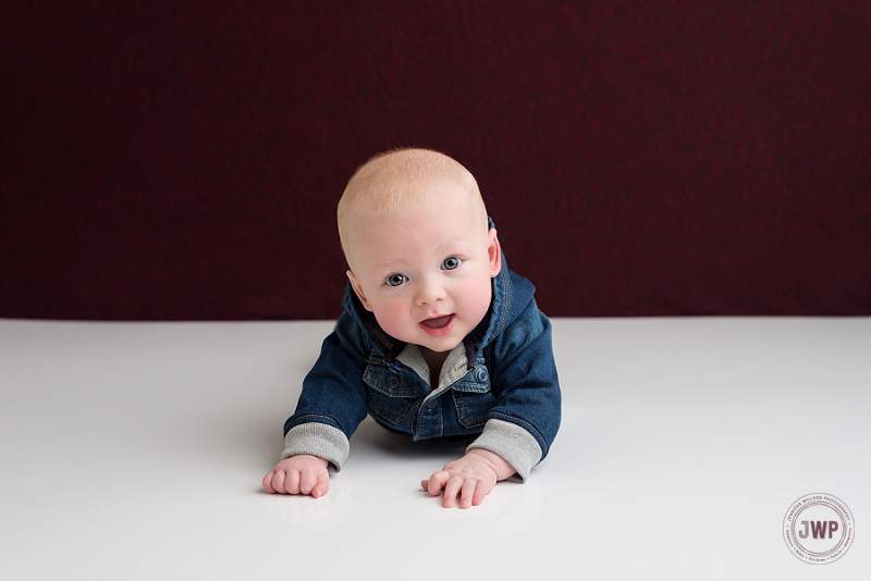 posed baby portrait 6 months old boy jean jacket burgundy backdrop Kingston Children Photographer