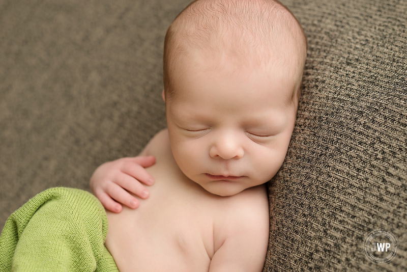 posed newborn picture boy green pants brown blanket on back Kingston Newborn Photographer