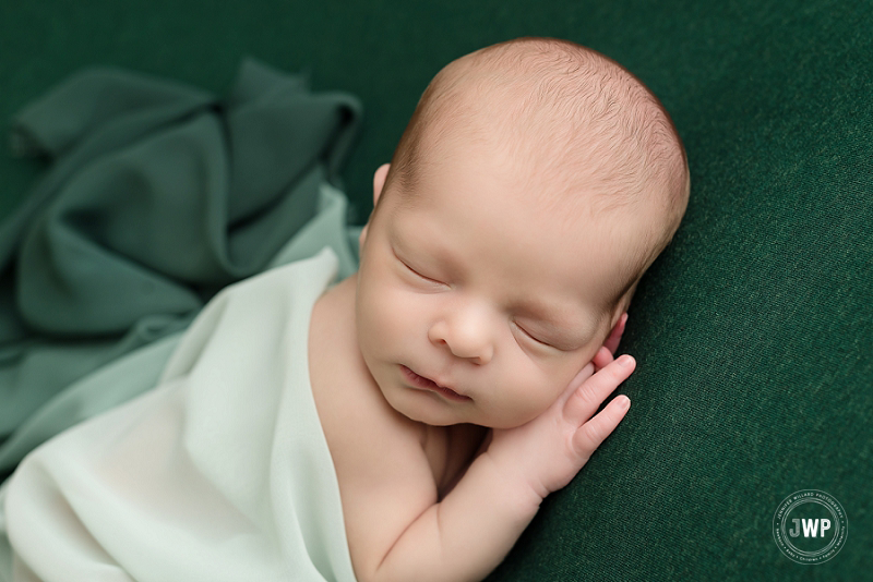 side lying posed newborn picture green blanket wrap Kingston Newborn Photographer