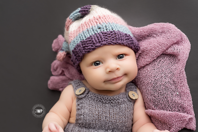 newborn portrait studio grey romper grey blanket purple striped hat YGK Photographer