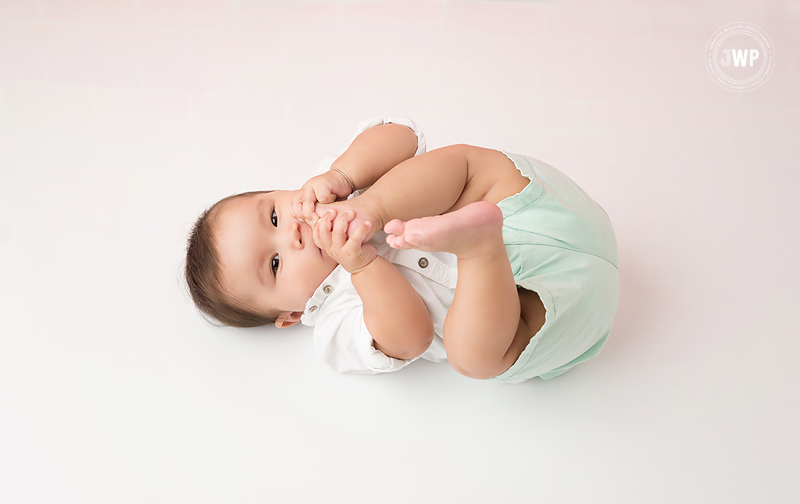 baby boy 7 months white backdrop eating toes Kingston Photographer