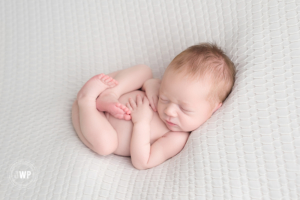 baby boy white blanket lying on back Kingston newborn photographer