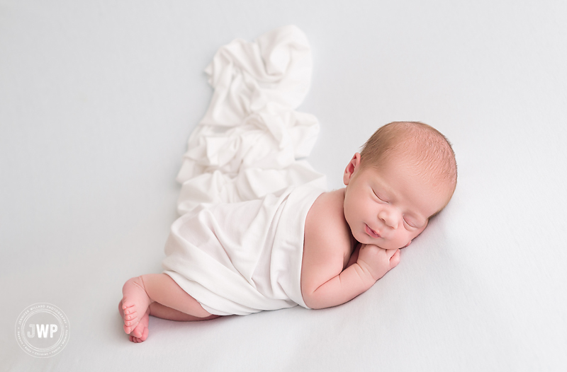 newborn boy lying down white wrap blanket Kingston baby photographer