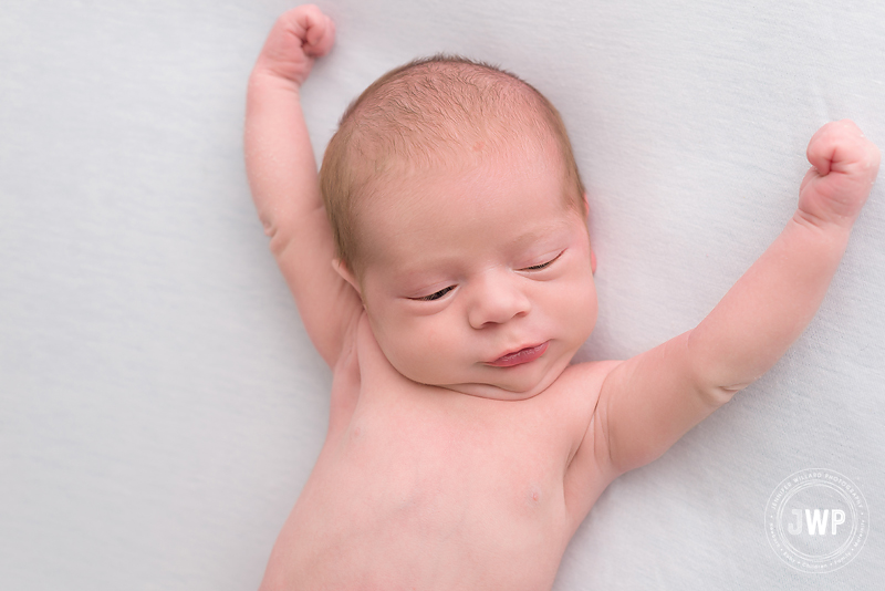 newborn boy stretching white blanket Kingston baby photographer