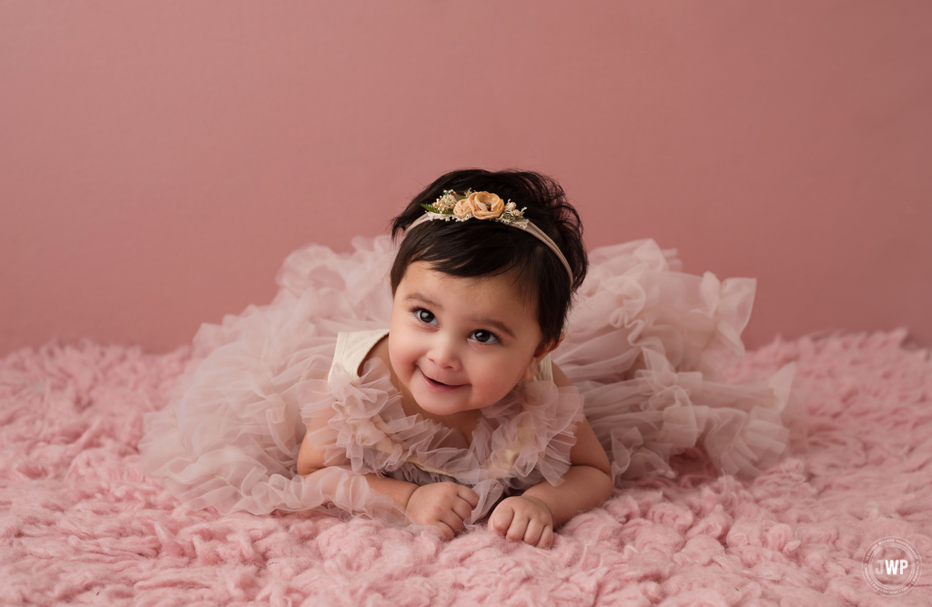 6 month old laying down girl blush pink ruffle dress flower headband Kingston baby photographer