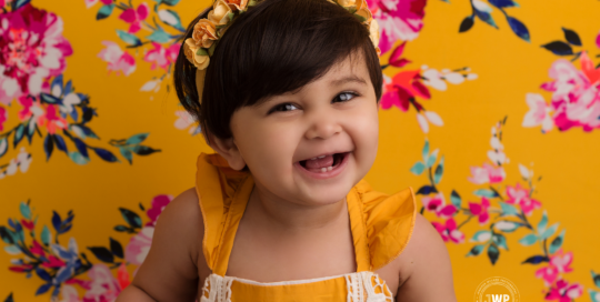 First birthday baby girl mustard yellow romper with pink and yellow backdrop Kingston cake smash photographer