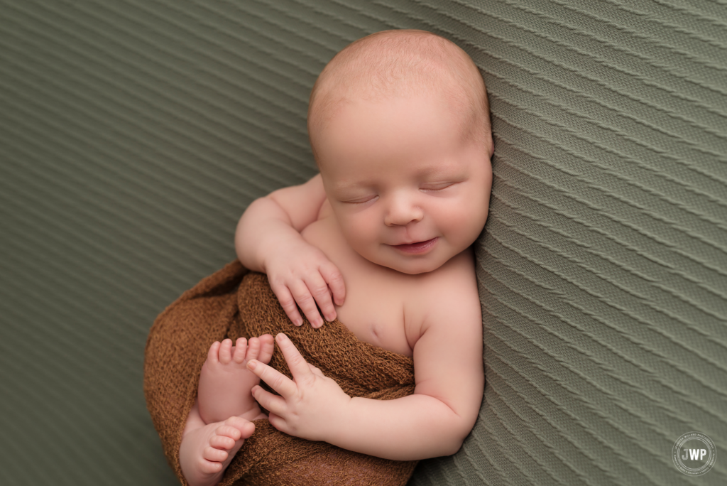 newborn boy smiling olive green blanket brown wrap Kingston baby photographer