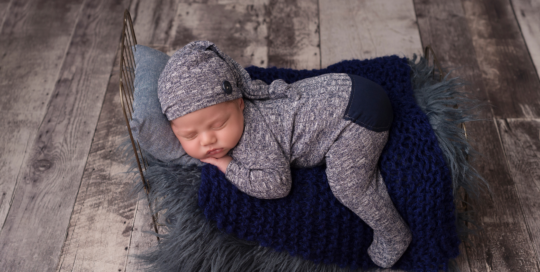 Newborn portrait grey wood floor blue romper pillows Kingston baby photographer