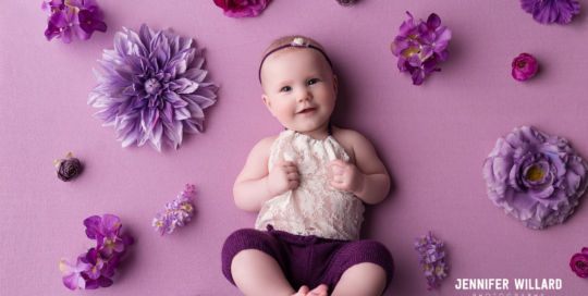 baby girl in purple and white romper with purple flowers
